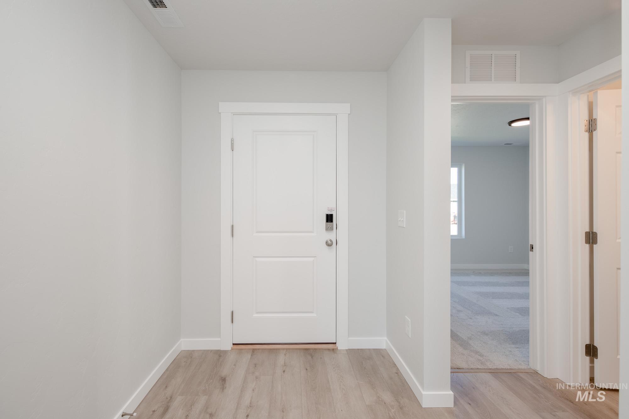 14092 Shiny Spruce Street Caldwell, ID 83607 - Photo 2 of 22 Entryway featuring light wood-finish flooring, white trim, and a white panel door with smart lock hardware