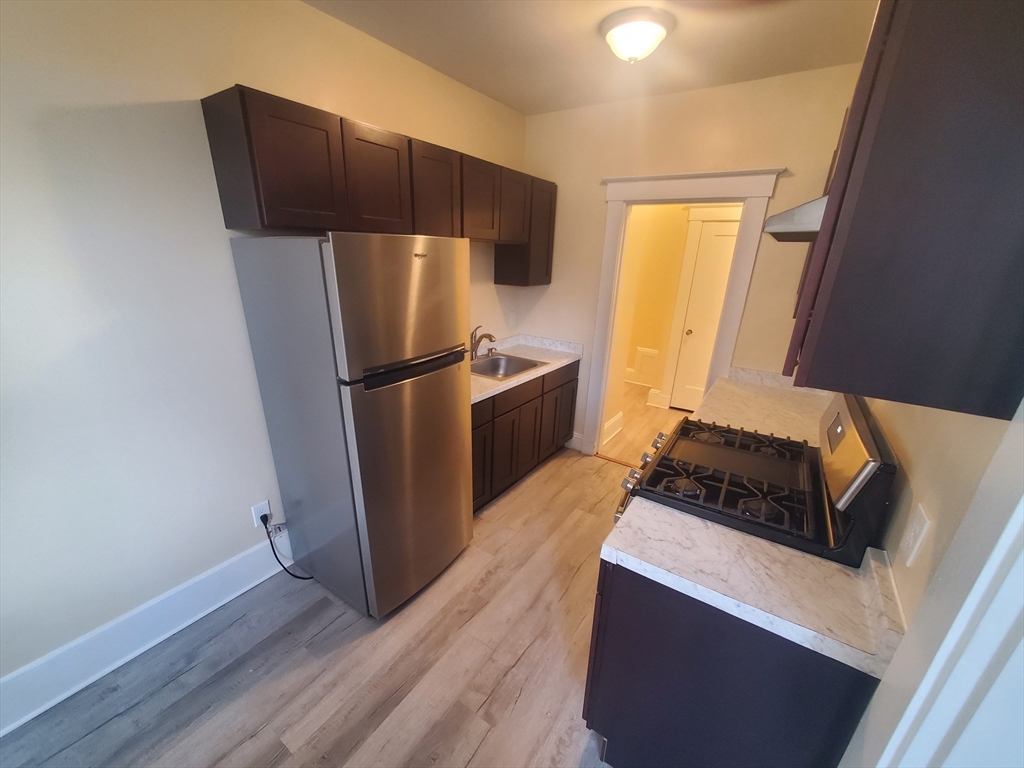 415 County Street, Unit 116 New Bedford, MA 02740 - Photo 2 of 14 a kitchen with a refrigerator sink and wooden floor