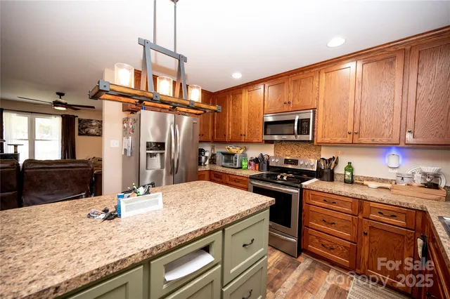 a kitchen with granite countertop a stove top oven microwave and refrigerator