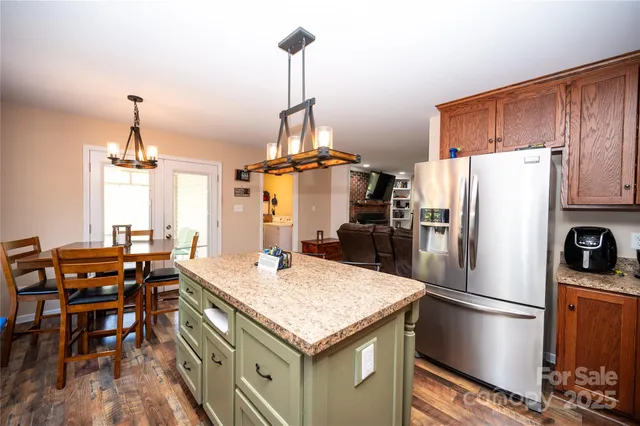 a kitchen with stainless steel appliances granite countertop a table chairs and refrigerator