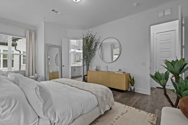 a bedroom with a bed a mirror and a potted plant