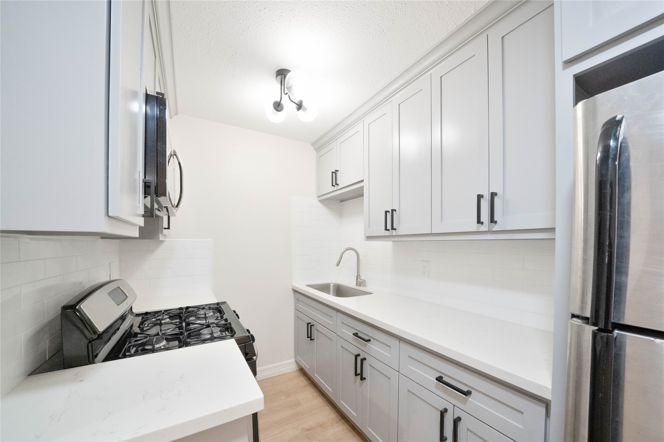 2703 Mason Street, Unit 2BD Houston, TX 77006 - Photo 11 of 19 a kitchen with white cabinets and stainless steel appliances