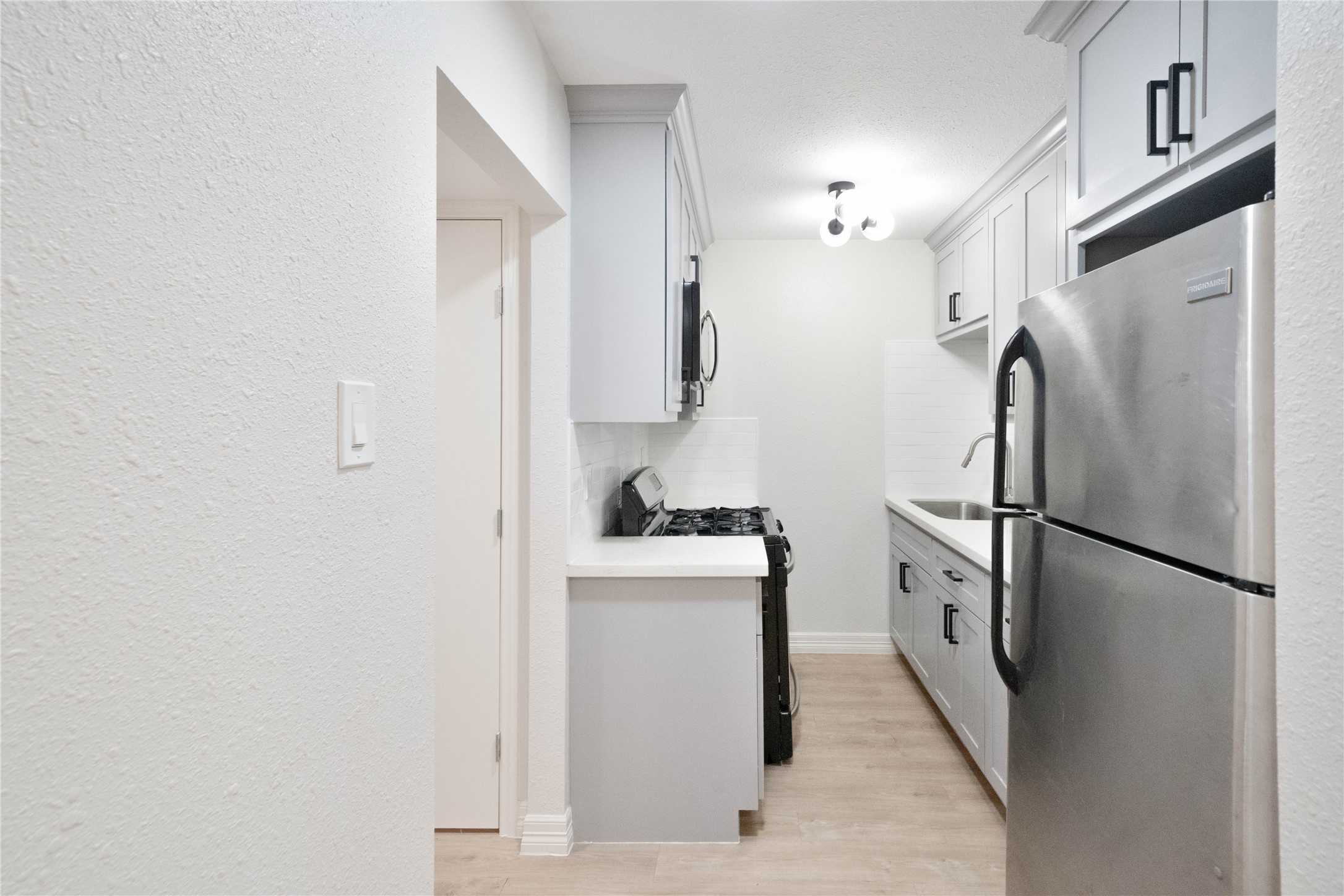 2703 Mason Street, Unit 2BD Houston, TX 77006 - Photo 10 of 19 a kitchen with stainless steel appliances a refrigerator a stove and white cabinets