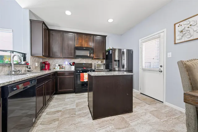 a kitchen with stainless steel appliances granite countertop a refrigerator and a stove top oven
