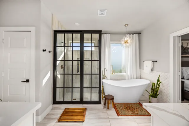 a spacious bathroom with a tub a sink and a large mirror next to a window