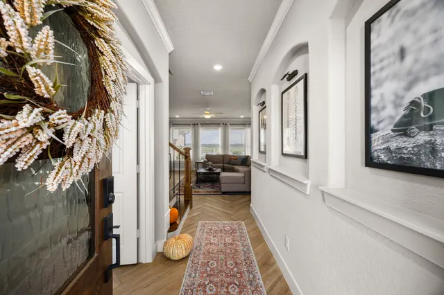 a view of a hallway with wooden floor and living room
