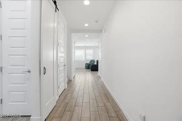 a view of a hallway with wooden floor and a bathroom