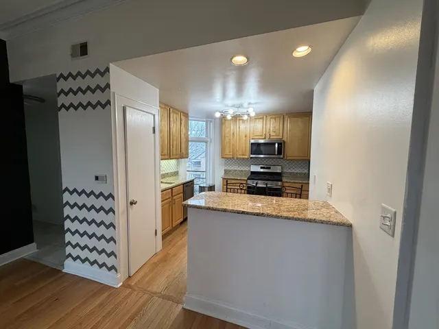 a kitchen with granite countertop a refrigerator and a stove top oven