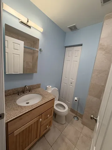 a bathroom with a granite countertop sink toilet and mirror