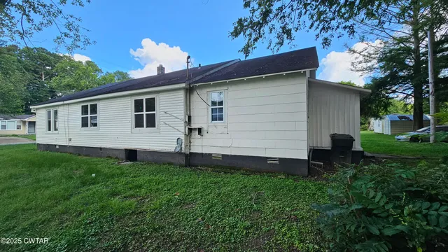 a view of a backyard with plants and a large tree