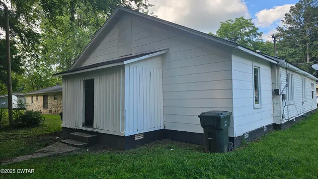 a view of backyard with potted plants and large tree