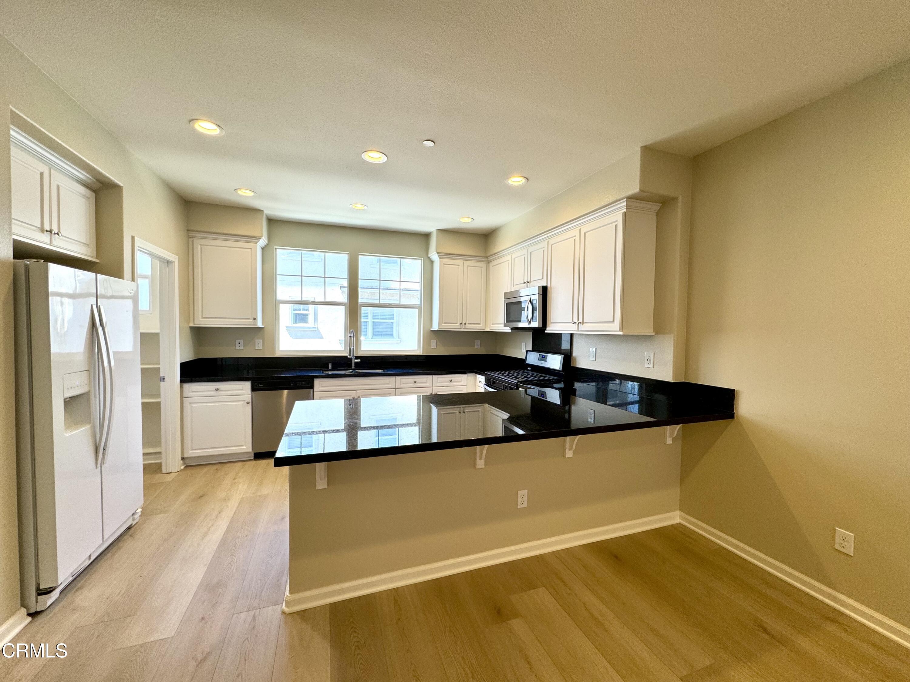 3667 Islander Walk Oxnard, CA 93035 - Photo 10 of 33 a large kitchen with stainless steel appliances a large counter top a stove and a refrigerator