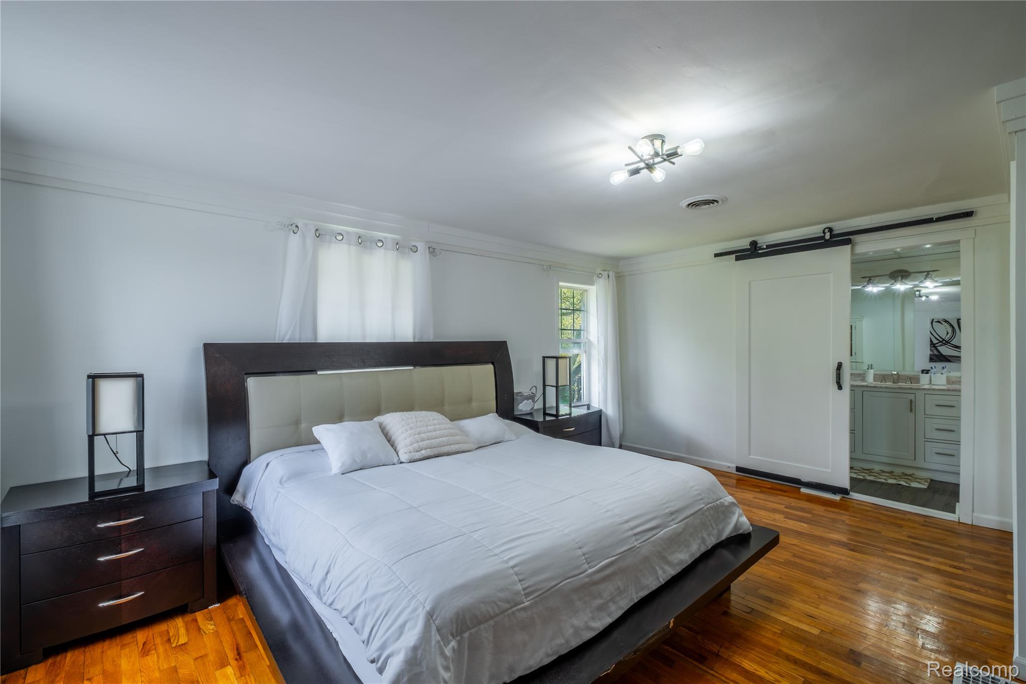 12164 Miller Road Lennon, MI 48449 - Photo 26 of 35 Bedroom featuring a barn door, hardwood / wood-style floors, and ensuite bath