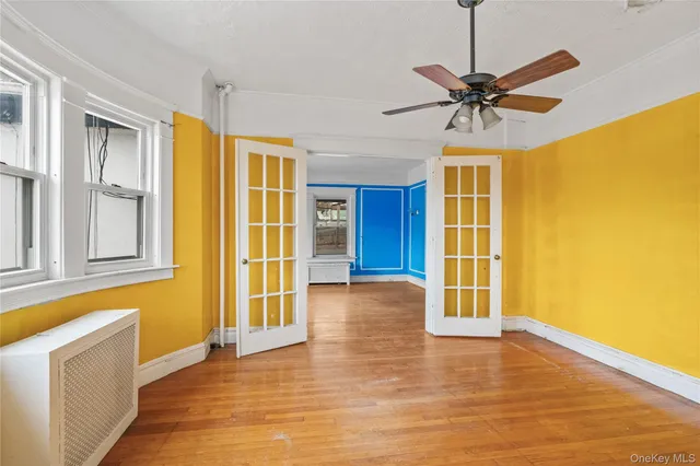 a view of an empty room with window and wooden floor