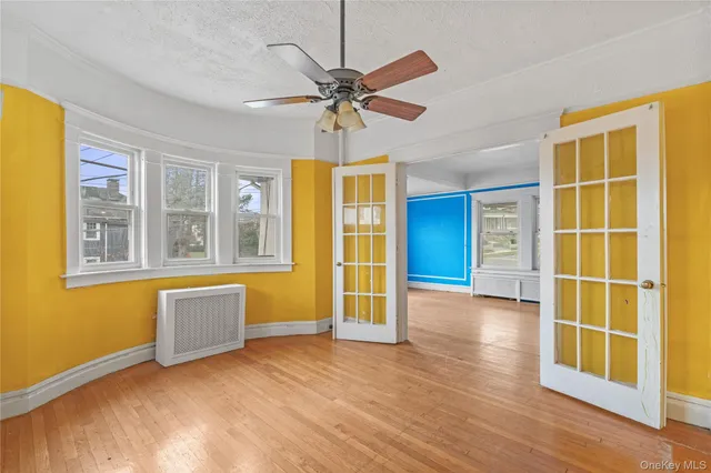 a view of an empty room with a window and wooden floor