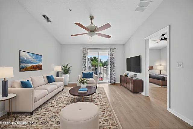 a living room with furniture a flat screen tv and a large window