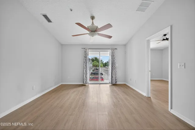 an empty room with wooden floor and windows