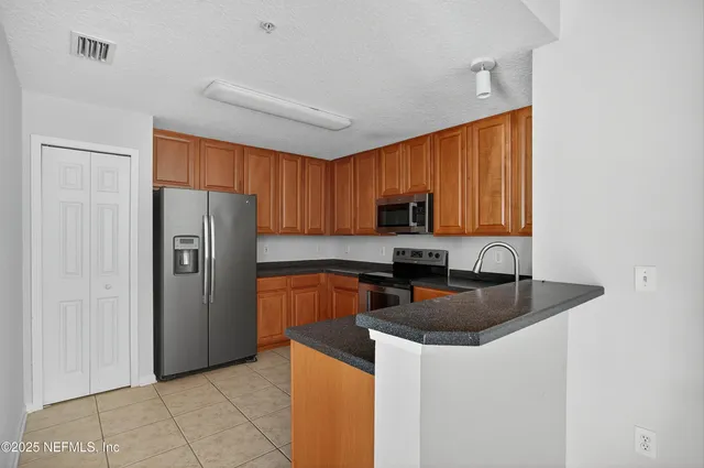 a kitchen with stainless steel appliances granite countertop a refrigerator a stove a sink and a microwave