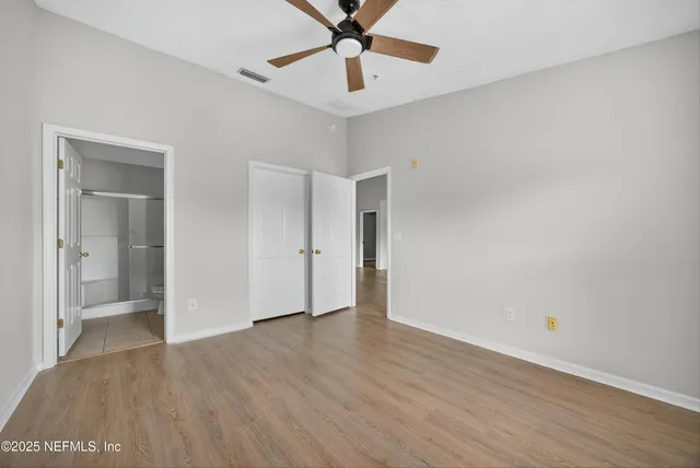 a view of an empty room with window and wooden floor