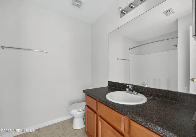 a bathroom with a granite countertop sink and a toilet