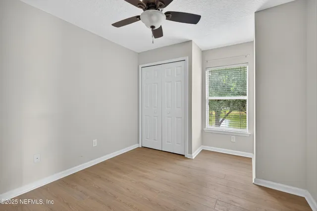 an empty room with a window and a fan