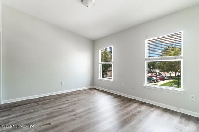a view of an empty room with wooden floor and a window
