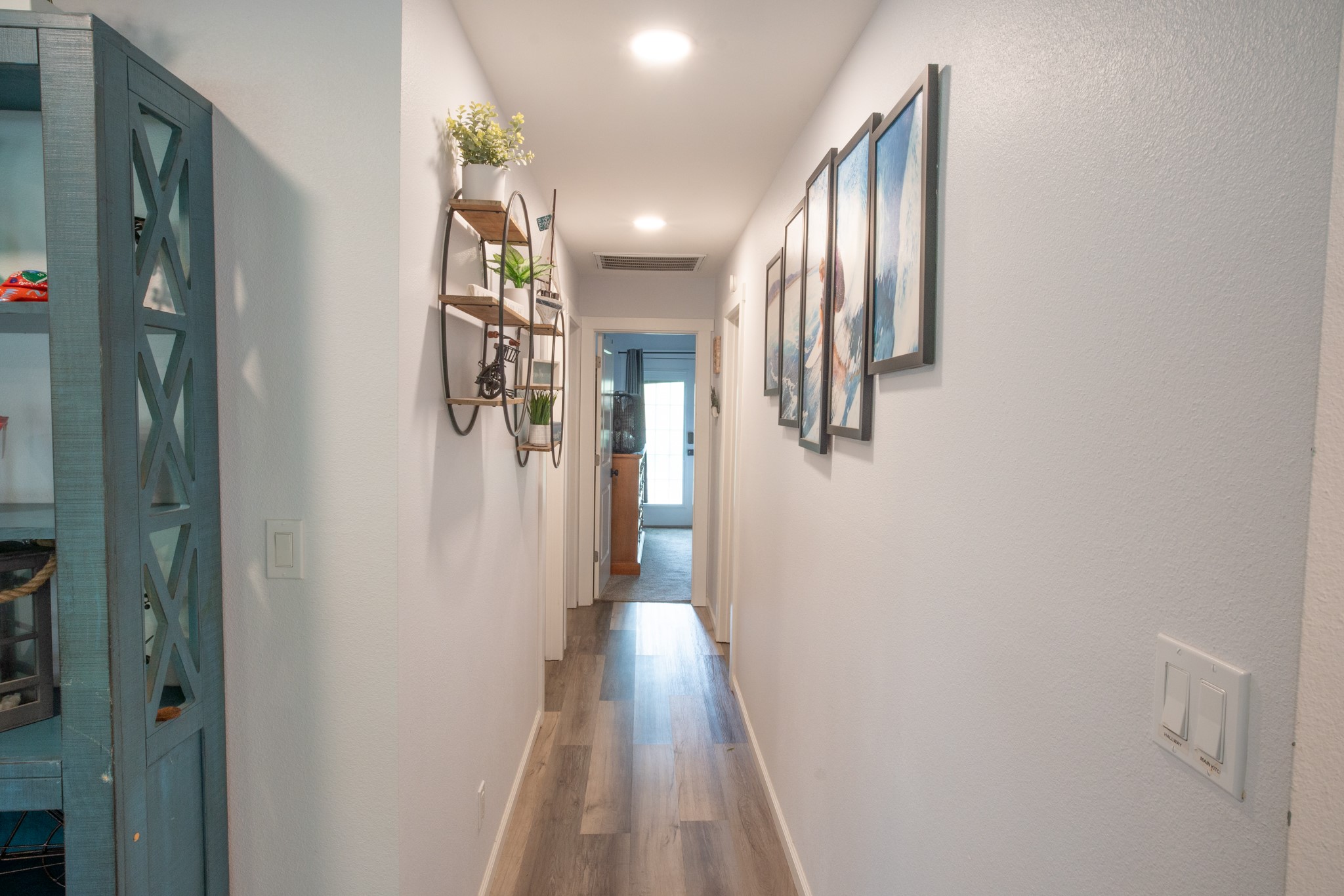 846 South Anderson Street Angleton, TX 77515 - Photo 13 of 30 Bright and inviting hallway with modern laminate wood look flooring. It leads to the primary bedroom, offering a cozy and contemporary feel.