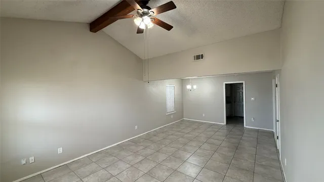 an empty room with a chandelier fan and windows