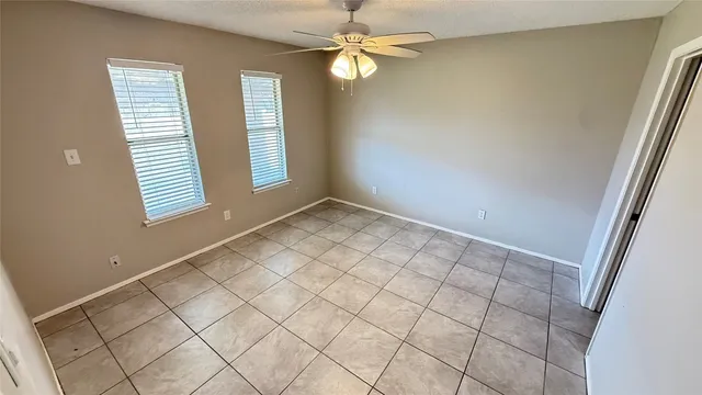 an empty room with windows and fan