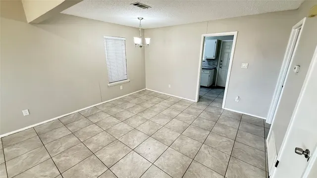 an empty room with white walls and chandelier fan