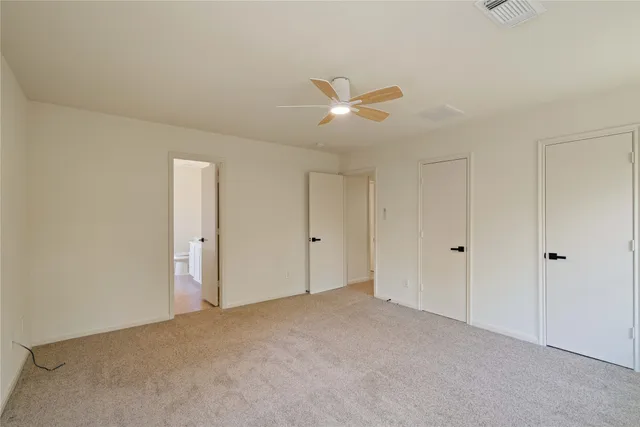a view of an empty room and chandelier fan