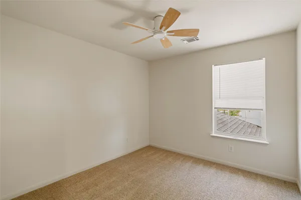 an empty room with a ceiling fan and window