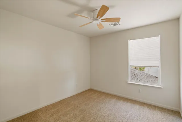 an empty room with a ceiling fan and window
