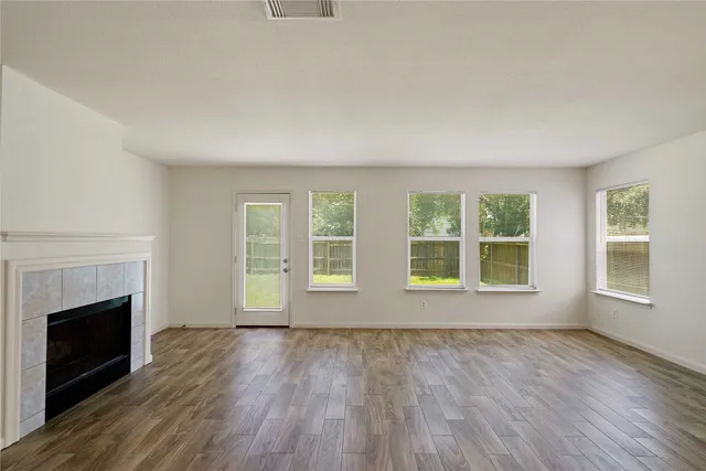 an empty room with wooden floor fireplace and windows
