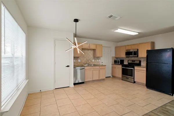 a kitchen with granite countertop a refrigerator and white cabinets