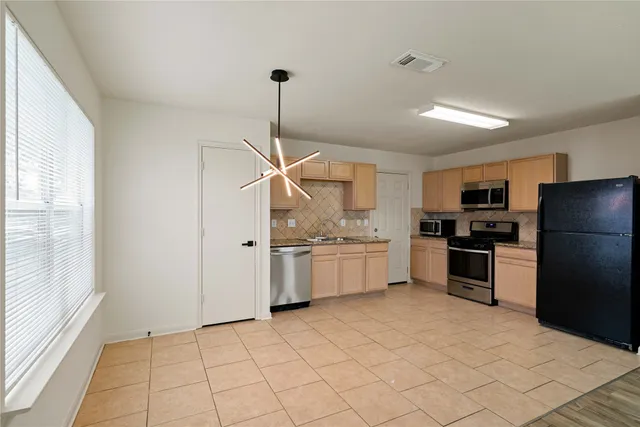 a kitchen with granite countertop a refrigerator and white cabinets