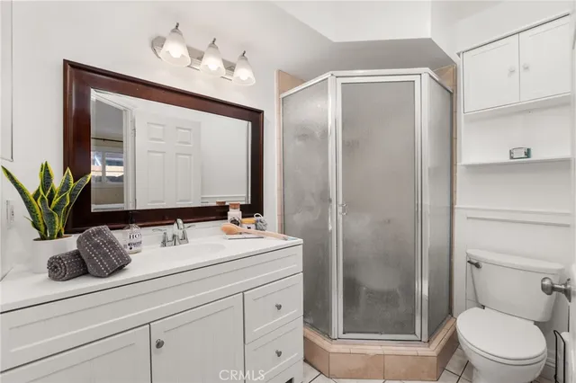 a bathroom with a granite countertop sink a toilet a mirror and shower
