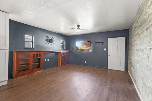 2576 Gramercy Avenue Ogden, UT 84401 - Photo 4 of 20 Unfurnished living room with a ceiling fan, dark wood-style floors, an accent wall, and a textured ceiling