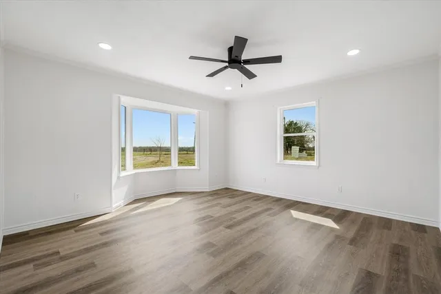 a view of an empty room with a window and wooden floor