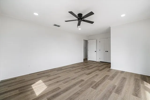 a view of empty room with wooden floor and ceiling fan