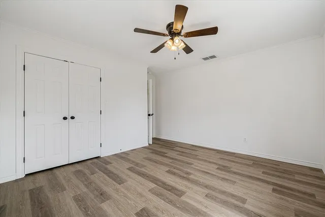 a view of a room with wooden floor and a ceiling fan
