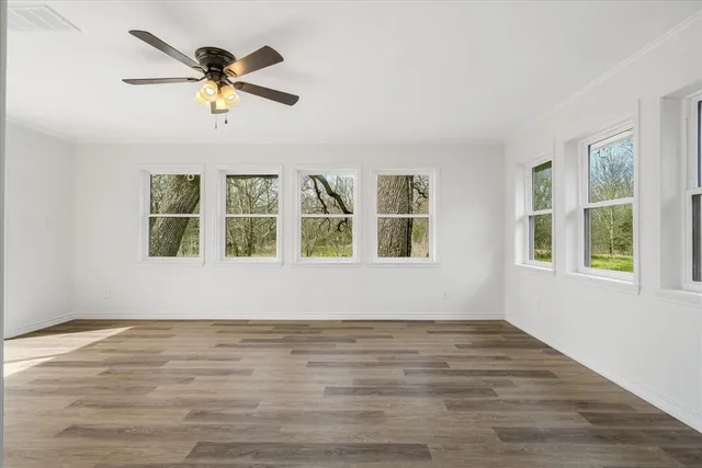 a view of empty room with wooden floor and fan