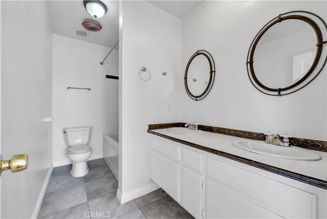 a bathroom with a granite countertop toilet a sink and a mirror