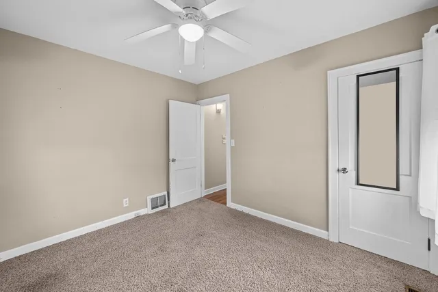 an empty room with a fan & a ceiling fan