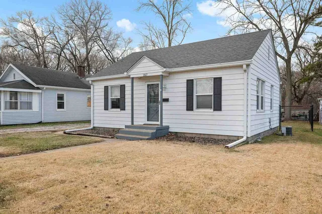 a view of a house with a yard and large tree