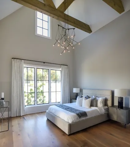 a spacious bedroom with a large bed and a chandelier