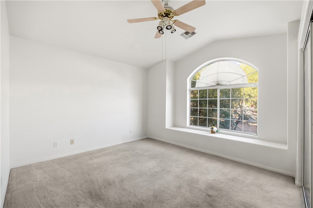 2853 Winchester Road Bullhead City, AZ 86442 - Photo 12 of 40 Room featuring an arched window with a built-in sill, a ceiling fan with light fixture, vaulted ceiling details, and neutral carpeting