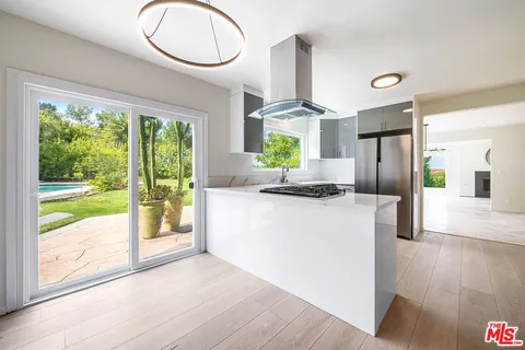 a kitchen with stainless steel appliances granite countertop a refrigerator a stove a sink and a large window