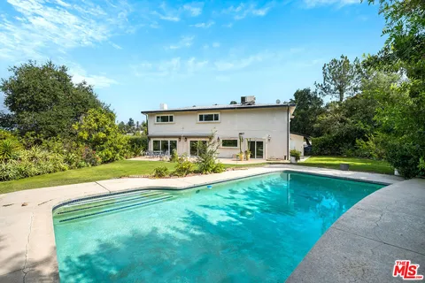 a view of a house with pool and a yard