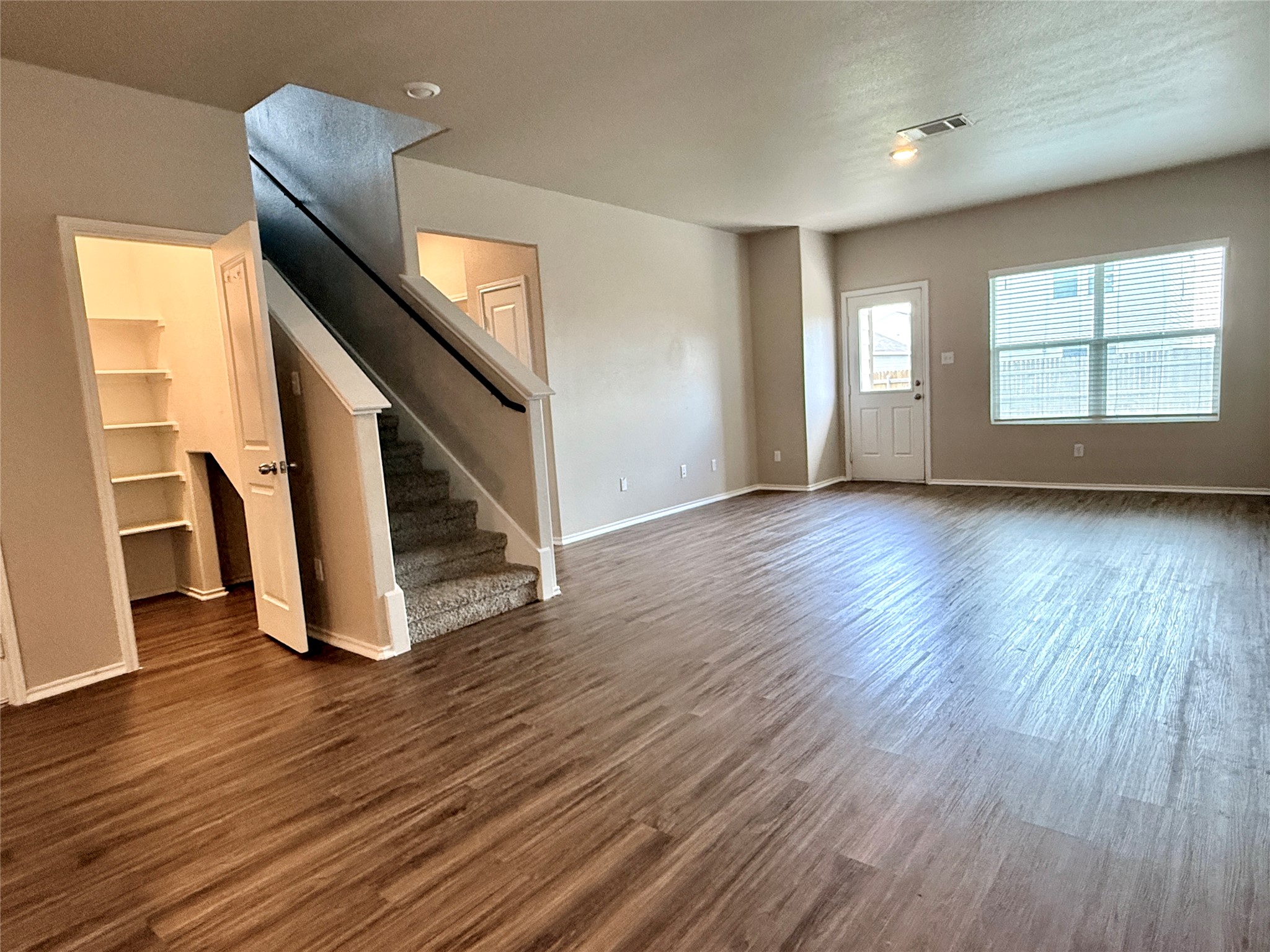 129 Perfect World Loop Jarrell, TX 76537 - Photo 10 of 31 A spacious room presents warm wood flooring and a carpeted staircase leading to upper levels.